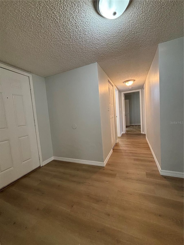 hall with wood-type flooring and a textured ceiling