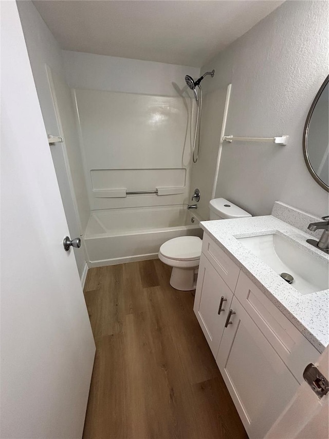 full bathroom with hardwood / wood-style flooring, washtub / shower combination, vanity, and toilet