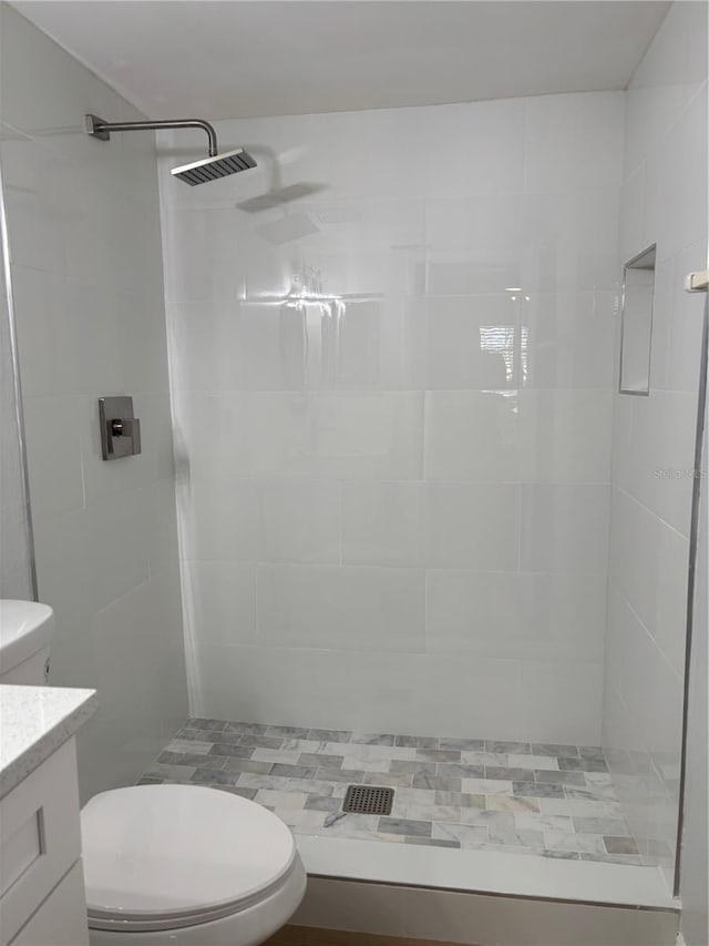 bathroom with vanity, a tile shower, and toilet