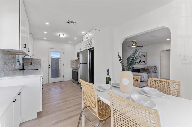 dining space with ceiling fan, sink, and light wood-type flooring