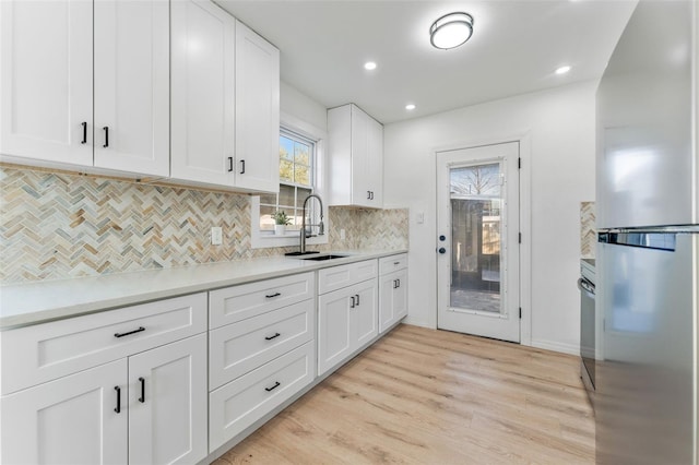 kitchen featuring stainless steel refrigerator, sink, and white cabinets