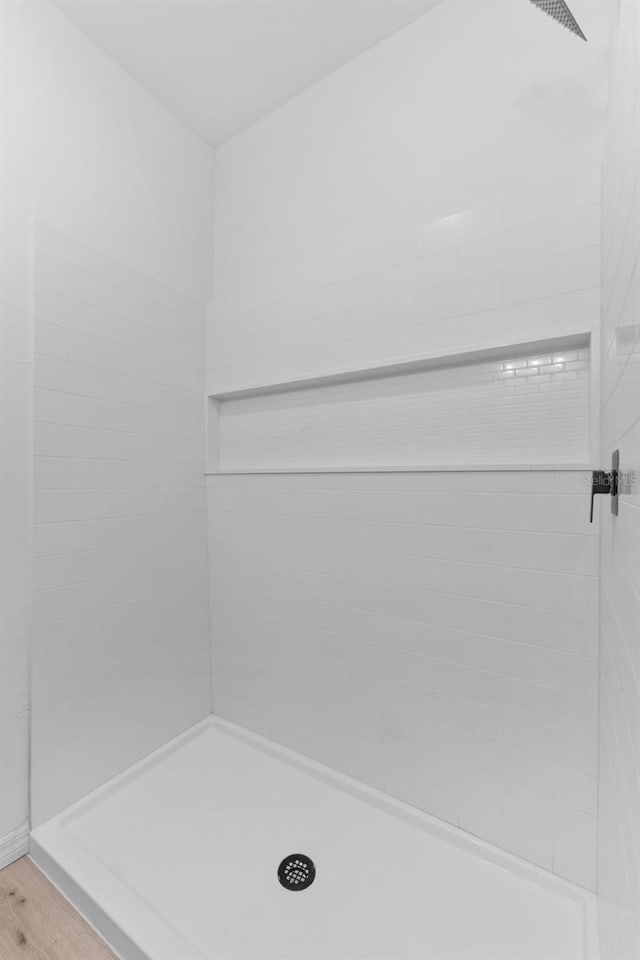 bathroom featuring wood-type flooring and tiled shower