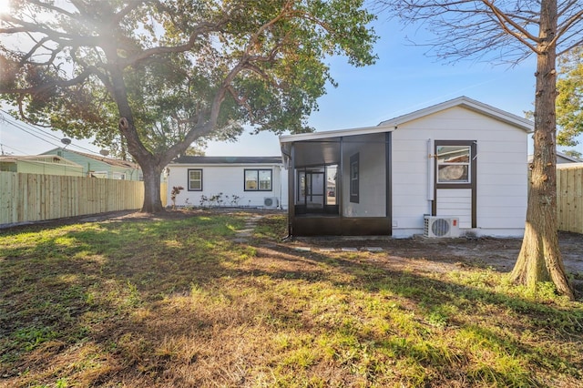 rear view of property featuring a yard, ac unit, and a sunroom