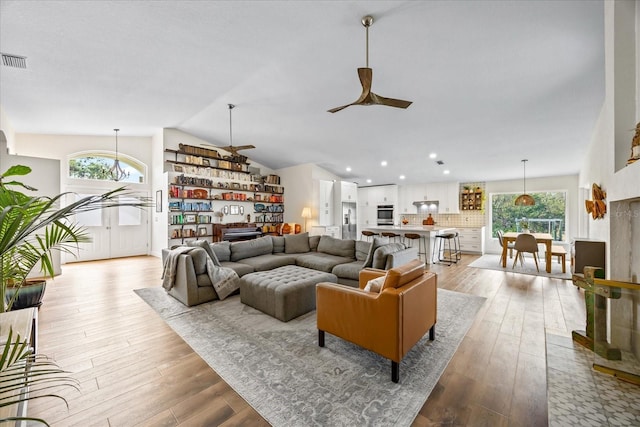 living room featuring vaulted ceiling, light hardwood / wood-style floors, and ceiling fan