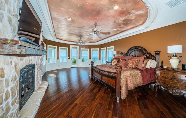 bedroom featuring dark hardwood / wood-style flooring, a tray ceiling, a fireplace, and ornamental molding