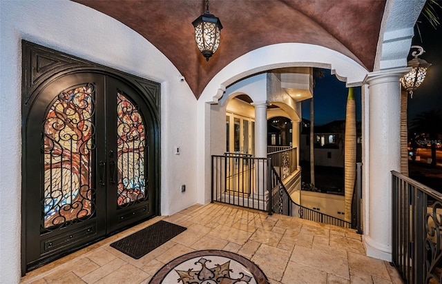 foyer entrance with lofted ceiling, french doors, and ornate columns