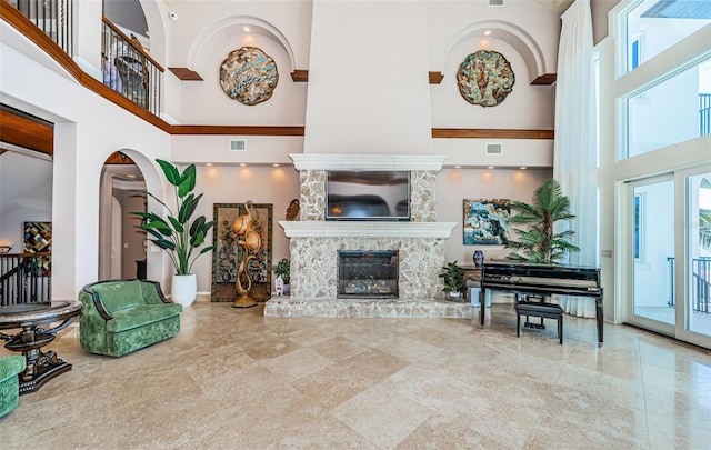 living room with a stone fireplace and a towering ceiling