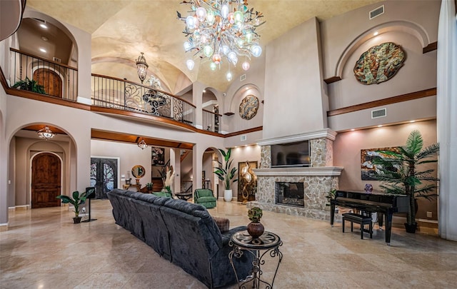 living room featuring an inviting chandelier, a stone fireplace, and vaulted ceiling