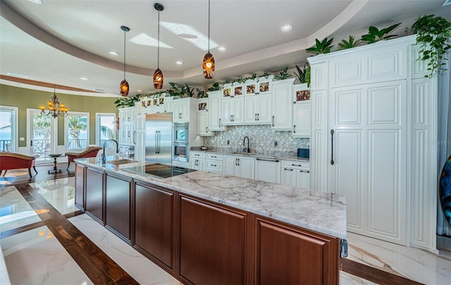 kitchen featuring a spacious island, sink, pendant lighting, stainless steel appliances, and white cabinets