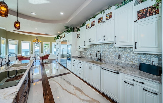 kitchen featuring sink, white cabinetry, decorative light fixtures, a raised ceiling, and black electric stovetop