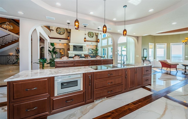 kitchen with black electric stovetop, a raised ceiling, and hanging light fixtures