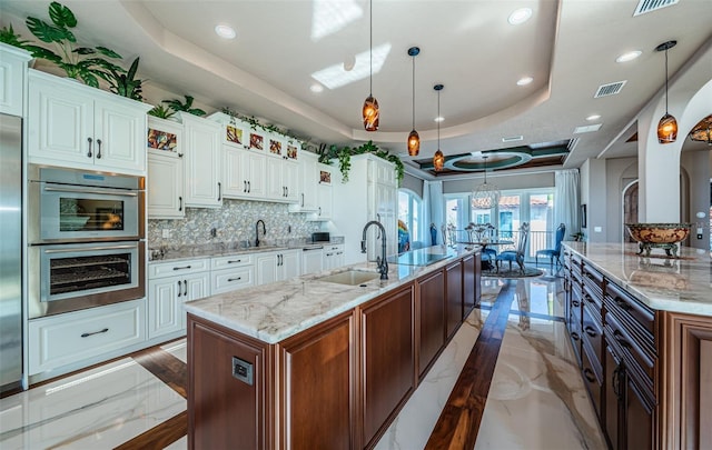 kitchen with a large island, a raised ceiling, and white cabinets