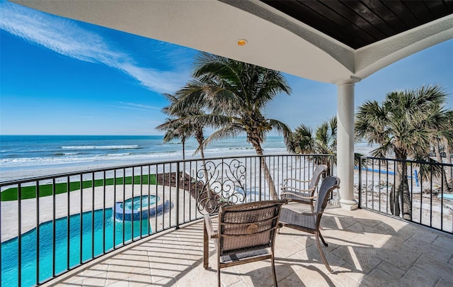 balcony featuring a view of the beach, a water view, and an in ground hot tub