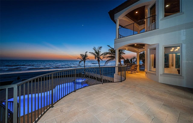 exterior space featuring a view of the beach, a water view, and a patio area