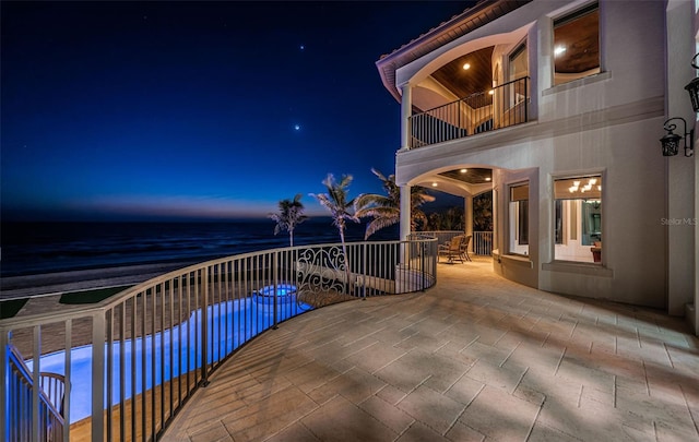 patio terrace at dusk featuring a balcony and a water view