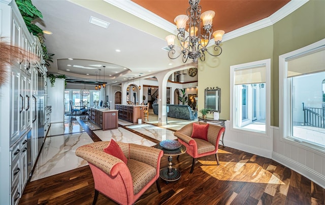 interior space with crown molding, dark wood-type flooring, a notable chandelier, and a tray ceiling