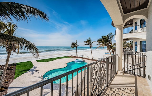 view of pool featuring a water view, a beach view, and a patio area