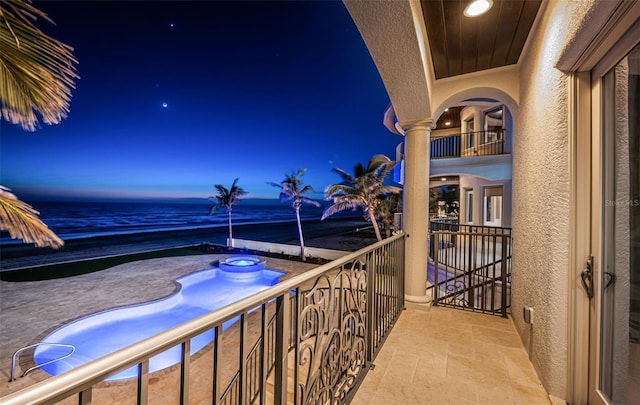 balcony at dusk with a view of the beach and a water view