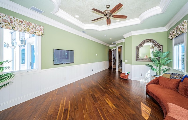 living room with dark hardwood / wood-style flooring, ceiling fan, a raised ceiling, crown molding, and a textured ceiling