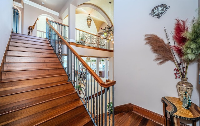 stairs with hardwood / wood-style floors, crown molding, and a high ceiling