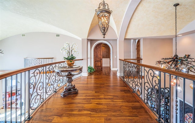 corridor featuring vaulted ceiling, dark hardwood / wood-style floors, and a chandelier