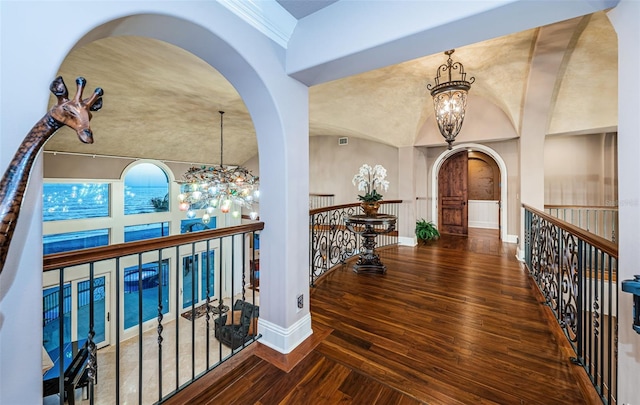 corridor featuring crown molding, dark wood-type flooring, a notable chandelier, and a towering ceiling