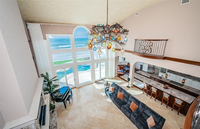 living room featuring high vaulted ceiling and a notable chandelier