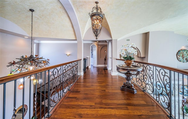 hallway with lofted ceiling, dark hardwood / wood-style flooring, and a notable chandelier