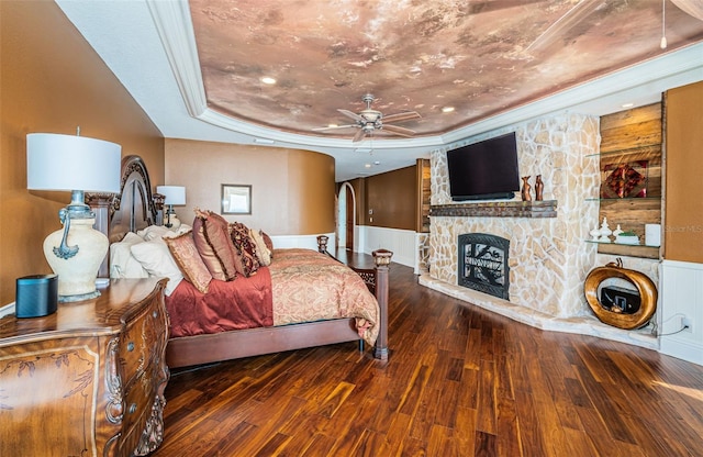 bedroom featuring hardwood / wood-style floors, a fireplace, ornamental molding, and a raised ceiling