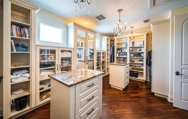 walk in closet with an inviting chandelier and dark wood-type flooring