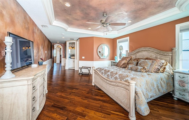 bedroom featuring dark hardwood / wood-style floors, ornamental molding, a tray ceiling, and multiple windows