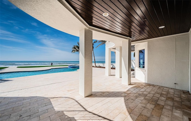 view of patio / terrace featuring a water view and a beach view