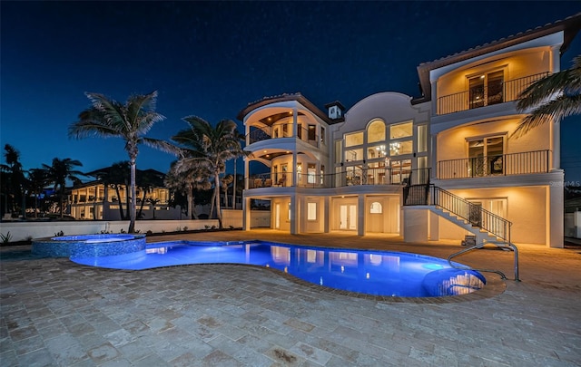 pool at twilight featuring an in ground hot tub and a patio