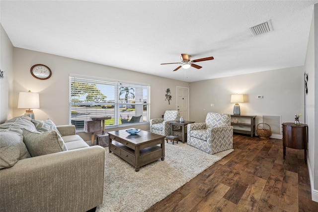 living room featuring ceiling fan, a textured ceiling, and dark hardwood / wood-style flooring