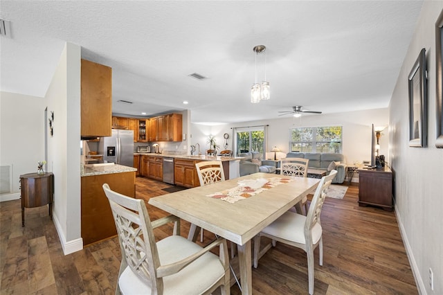 dining area featuring dark wood-type flooring, ceiling fan, sink, and a textured ceiling