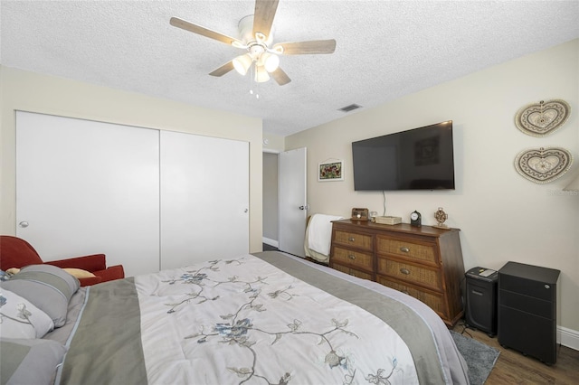 bedroom featuring ceiling fan, dark wood-type flooring, a textured ceiling, and a closet