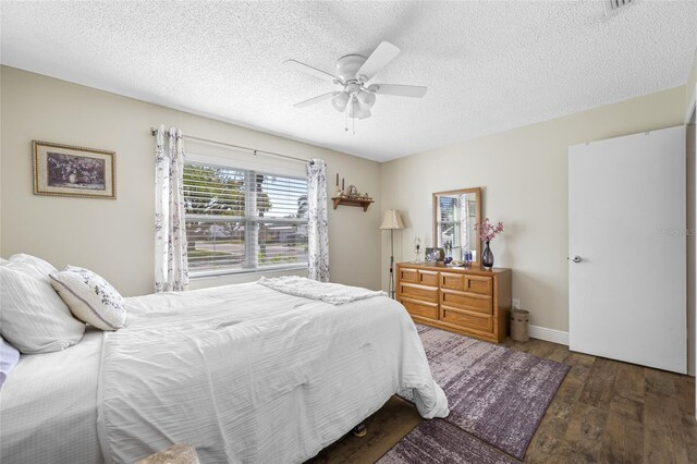 bedroom with ceiling fan, dark wood-type flooring, and a textured ceiling