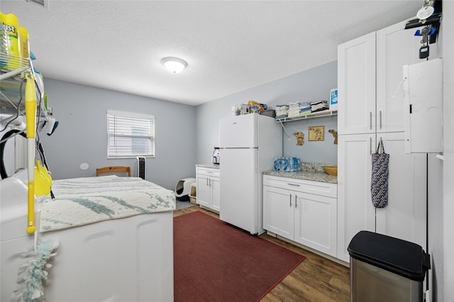 clothes washing area with dark wood-type flooring and a textured ceiling