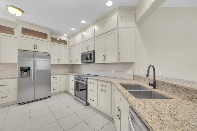 kitchen with sink, tasteful backsplash, light tile patterned floors, stainless steel appliances, and light stone countertops