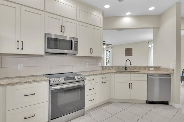 kitchen with sink, backsplash, stainless steel appliances, and light stone countertops