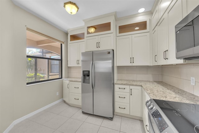 kitchen featuring light tile patterned floors, appliances with stainless steel finishes, white cabinetry, light stone countertops, and decorative backsplash