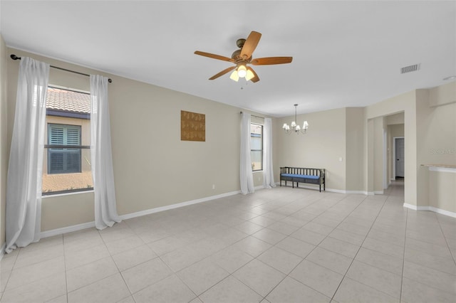 tiled empty room with ceiling fan with notable chandelier