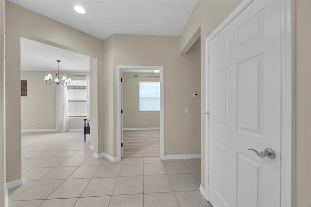 corridor featuring a notable chandelier and light tile patterned floors