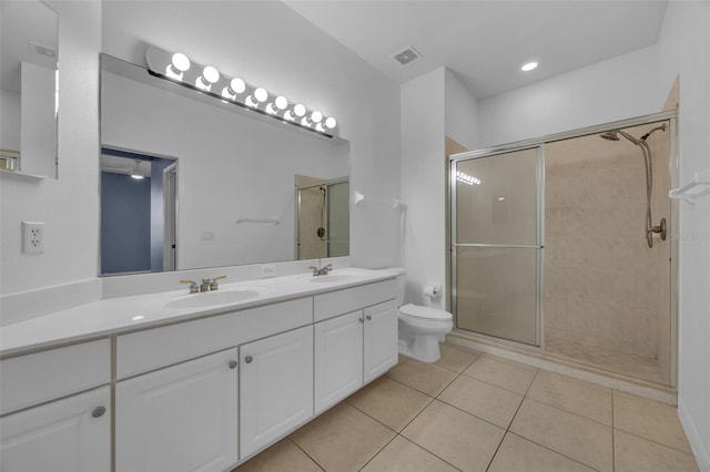 bathroom with a shower with door, vanity, tile patterned flooring, and toilet