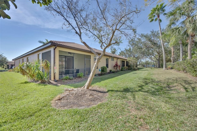 view of yard featuring ceiling fan and a sunroom