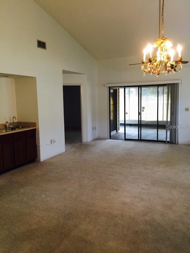 unfurnished living room with light colored carpet, high vaulted ceiling, a chandelier, and sink