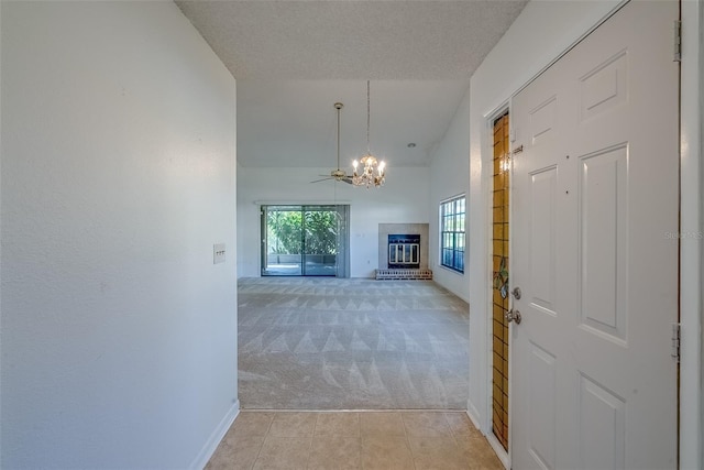 hall featuring light tile patterned floors, light carpet, baseboards, vaulted ceiling, and an inviting chandelier