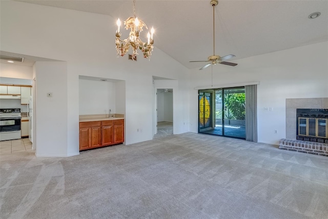 unfurnished living room with ceiling fan, high vaulted ceiling, light colored carpet, a fireplace, and a sink