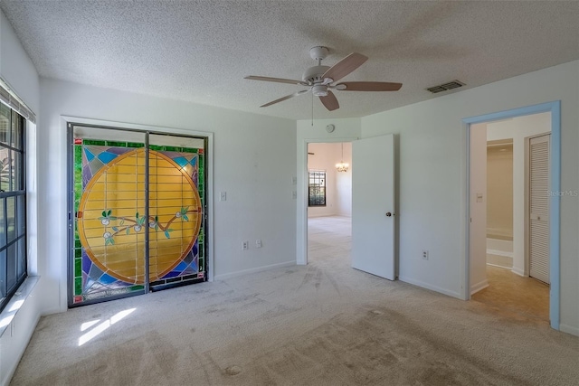 empty room with visible vents, plenty of natural light, a textured ceiling, and carpet flooring