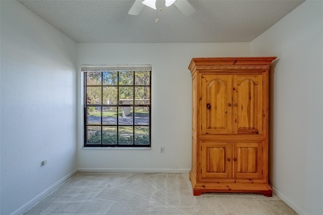 spare room featuring a ceiling fan, light carpet, a textured ceiling, and baseboards